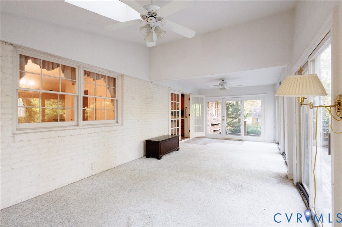 Sunroom featuring vaulted ceilings, a skylight, painted brick walls, dual ceiling fans, and multiple sets of glass-paned French doors
