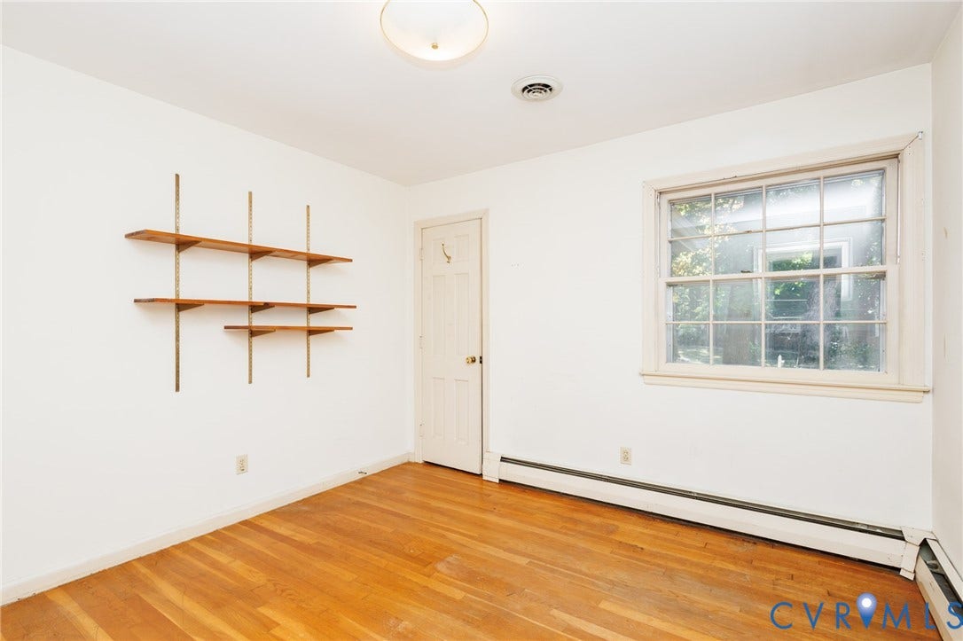 Interior room featuring wood-finish flooring, a multi-pane window, and wall-mounted shelving