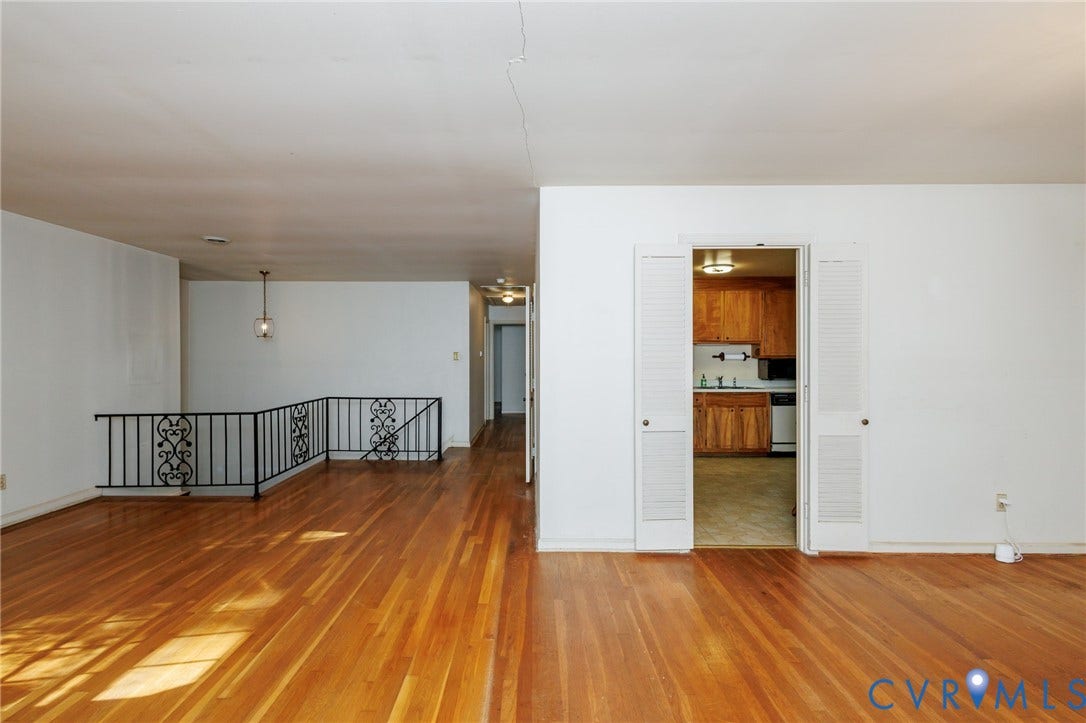 Wood-finish flooring, wrought iron staircase railing, and louvered double-door entry