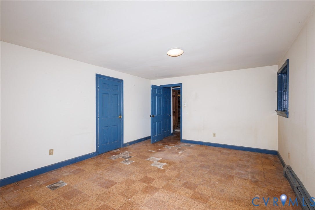 Interior room featuring checkerboard-patterned floor tiles, two blue-painted six-panel doors, and a single window with a blue-painted frame