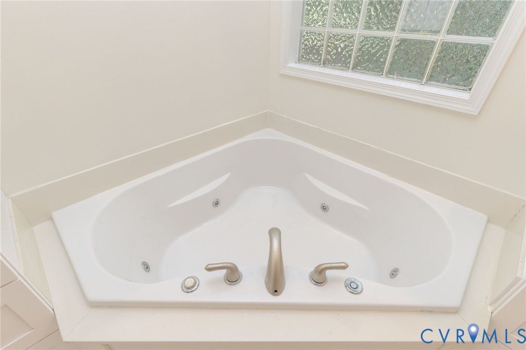 13742 Spyglass Hill Circle, Chesterfield, VA 23832 Corner soaking jetted tub featuring a white surround, brushed nickel faucet fixtures, and a framed window with obscured glass