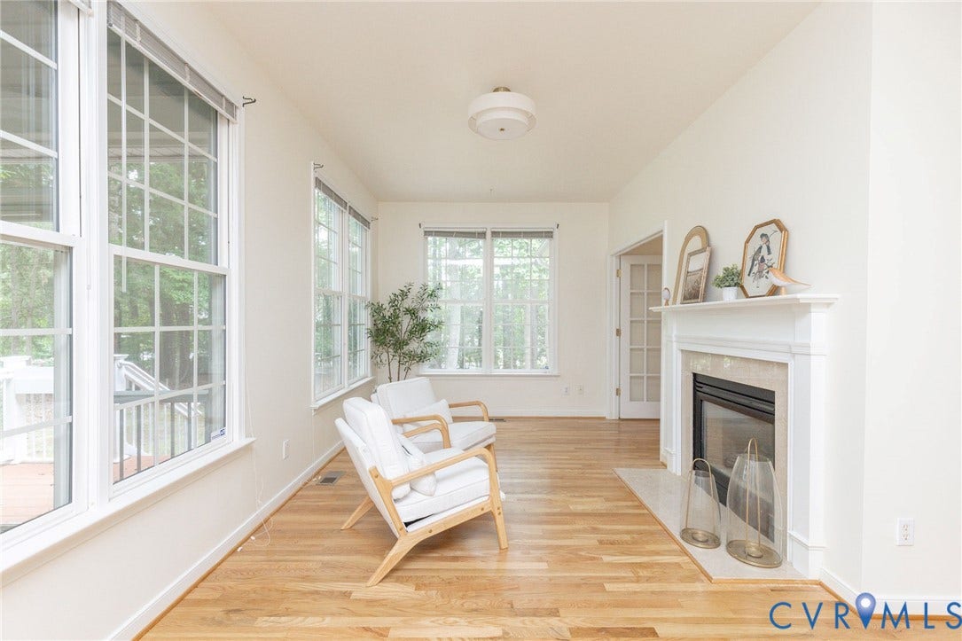 13742 Spyglass Hill Circle, Chesterfield, VA 23832 Sunroom featuring wood-finish flooring, multi-pane windows, and a fireplace with a stone surround and white mantle, complemented by a central flush-mount ceiling light