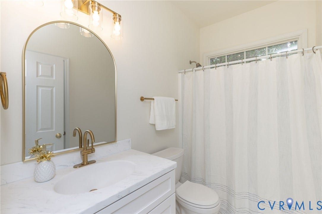 13742 Spyglass Hill Circle, Chesterfield, VA 23832 Arched vanity mirror with metallic frame, brass-finish faucet, stone-surfaced countertop, and multi-bulb vanity light fixture