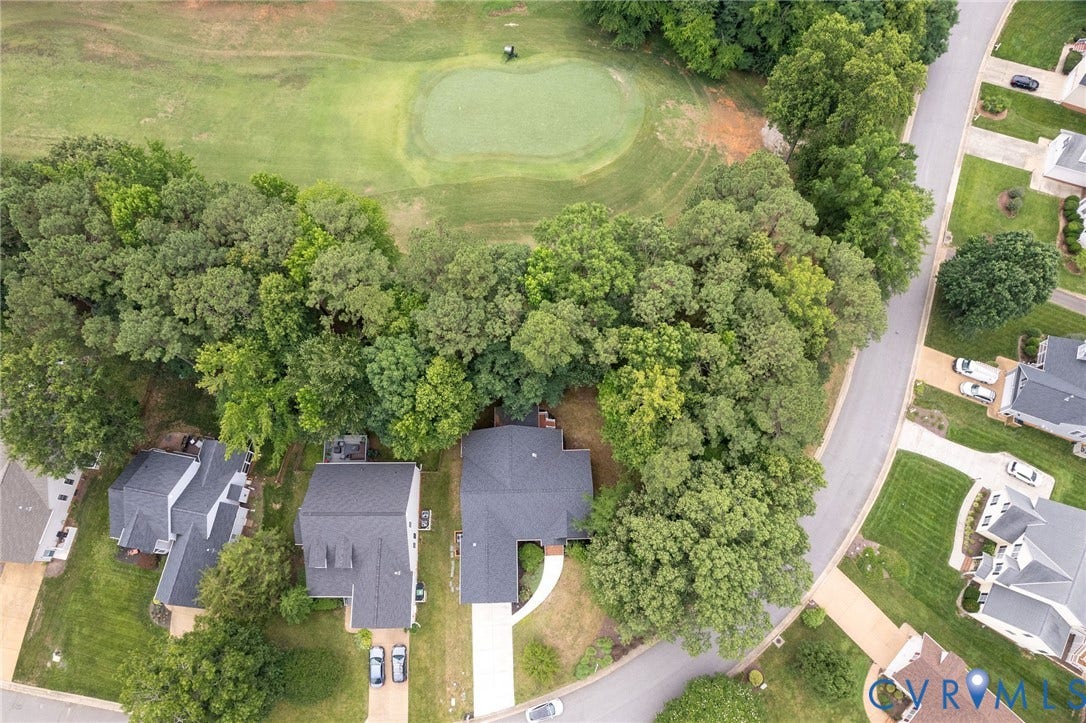 13742 Spyglass Hill Circle, Chesterfield, VA 23832 Aerial perspective featuring a residential lot with mature canopy trees, a concrete driveway, and direct proximity to a golf course putting green