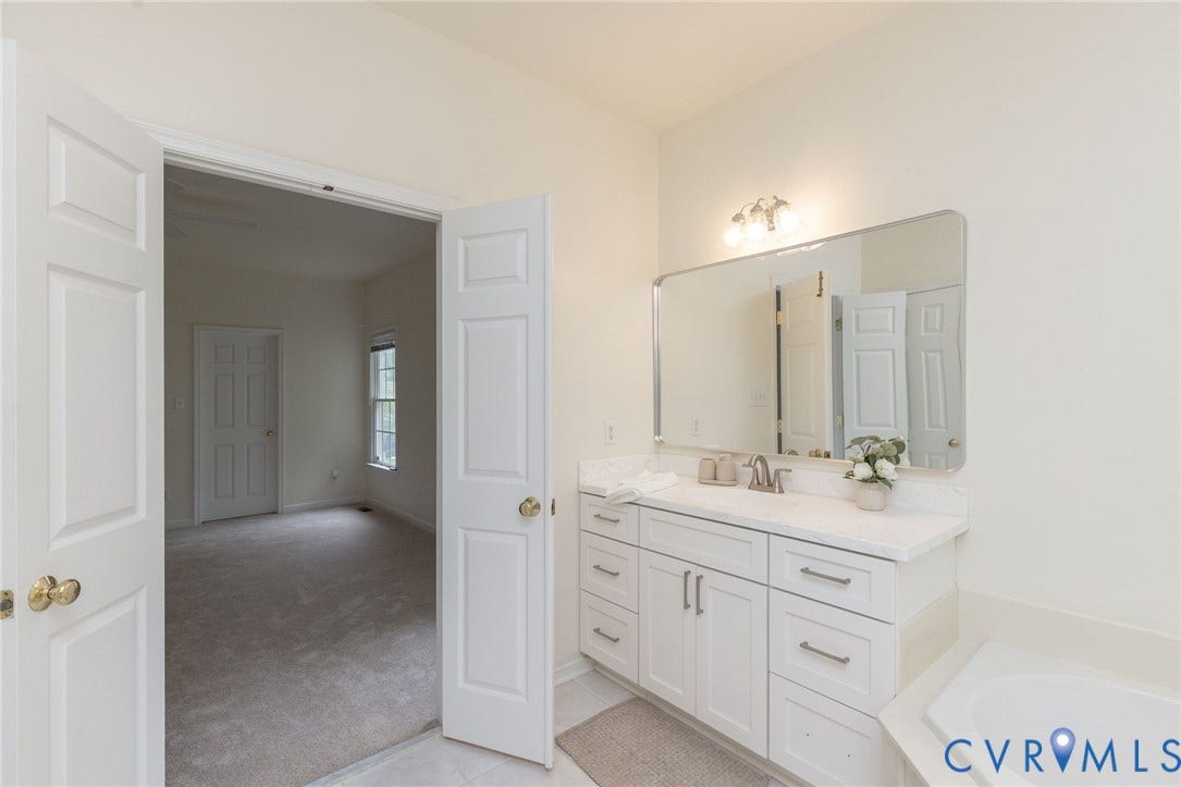 13742 Spyglass Hill Circle, Chesterfield, VA 23832 White cabinetry vanity with stone-finish countertop, undermount sink, multi-drawer storage, and large wall-mounted mirror with integrated light fixture