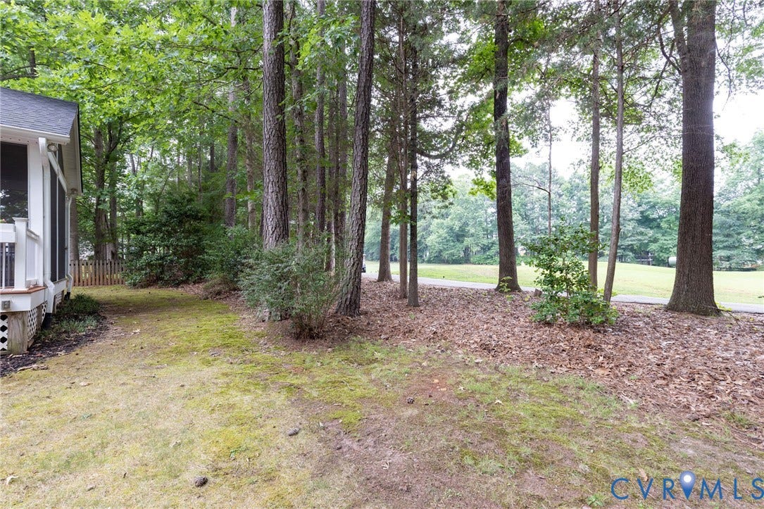 13742 Spyglass Hill Circle, Chesterfield, VA 23832 Ground-level deck featuring a partial white railing, surrounded by mature trees and established landscaping