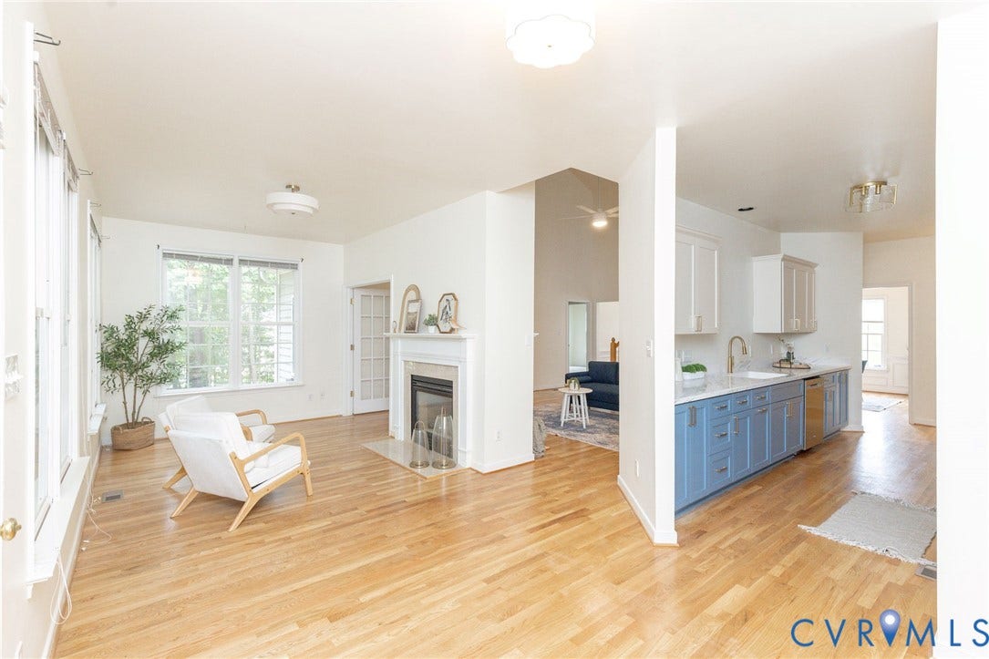 13742 Spyglass Hill Circle, Chesterfield, VA 23832 Living area with wood-finish flooring and a fireplace featuring a white mantel, kitchen cabinetry with a two-tone color scheme, quartz countertops, and stainless steel dishwasher