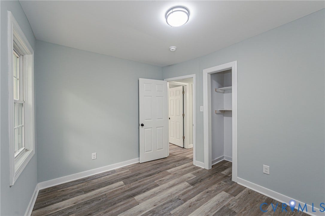 Wood-finish flooring throughout, white trim, and a built-in closet with shelving