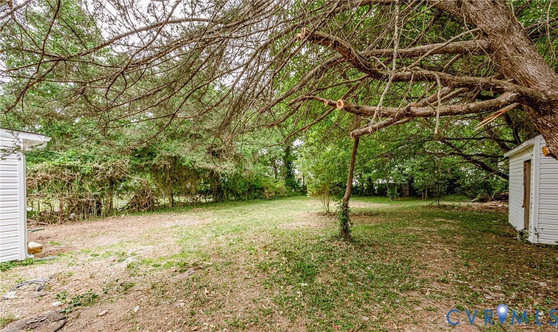 Expansive green lawn with mature trees and a white vinyl-sided storage shed