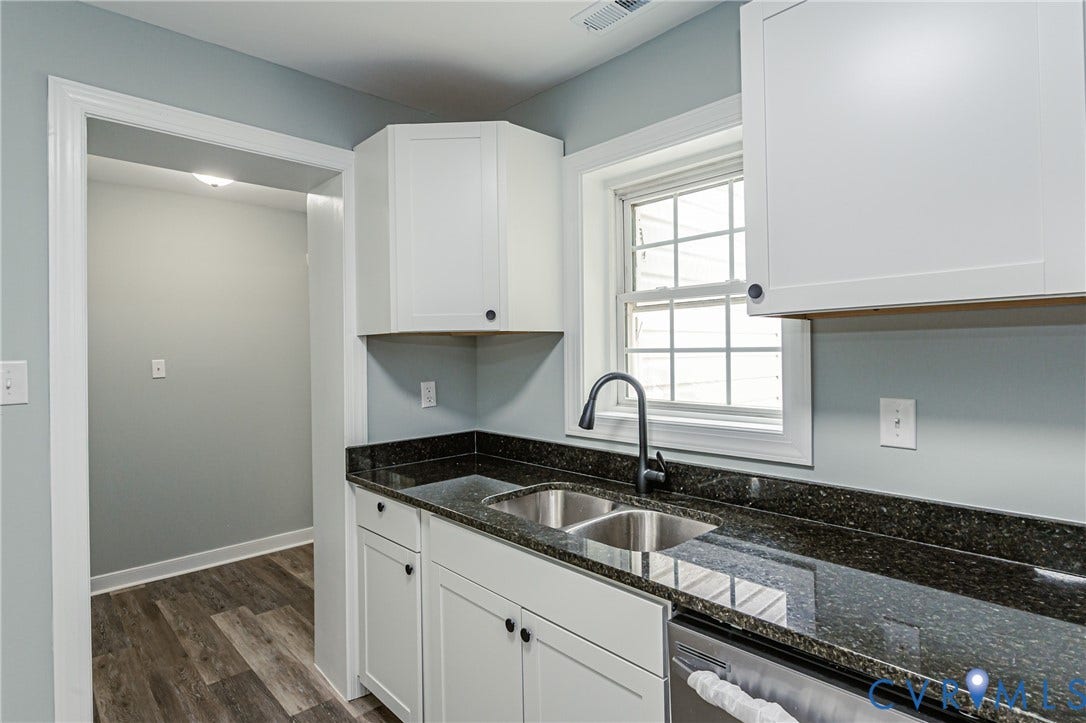 Kitchen featuring white cabinetry, dark speckled countertops, a stainless steel double basin sink with a gooseneck faucet, and wood-finish flooring