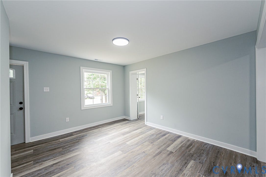 Wood-finish flooring, light blue wall paint, white trim, recessed light, and a window with white casing