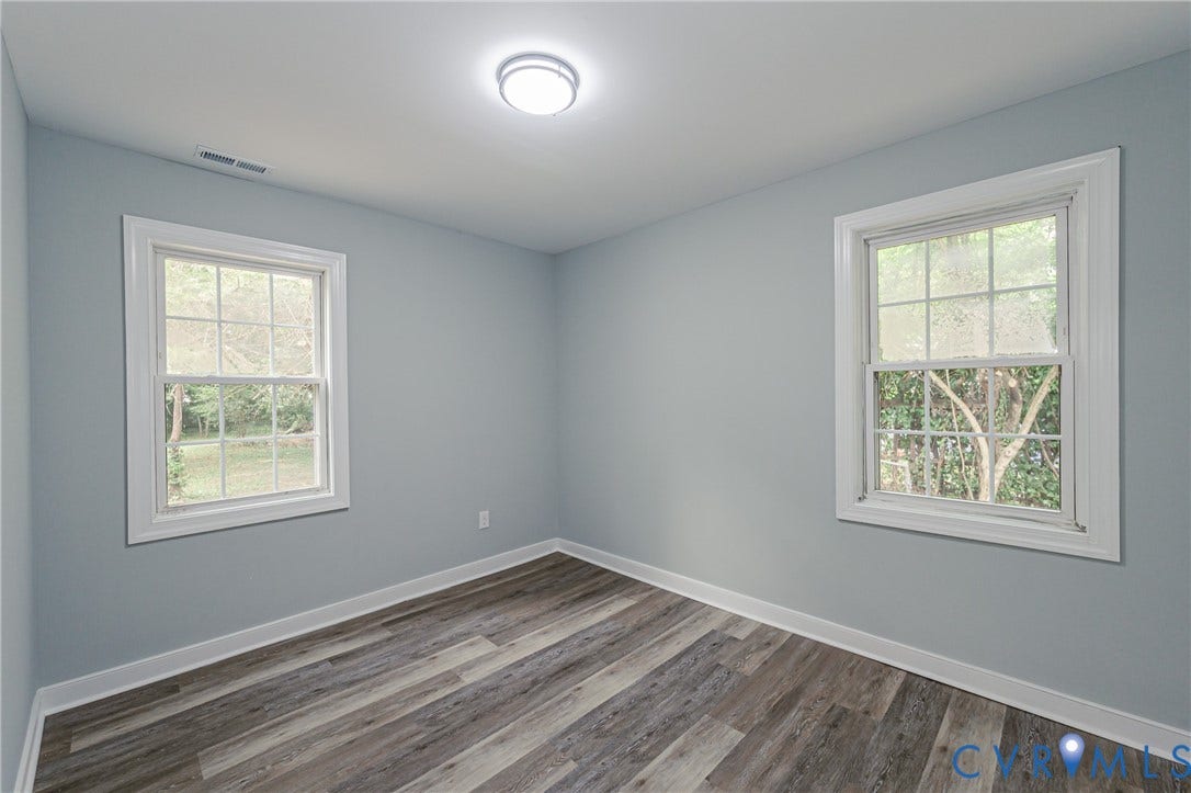Wood-finish flooring, white trim, and two windows with exterior views