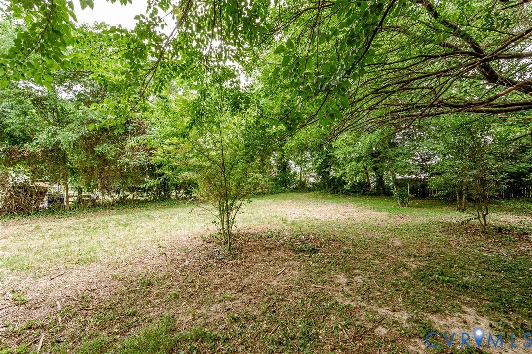 Expansive outdoor space featuring a combination of grass and natural ground cover, bordered by mature trees and varied foliage