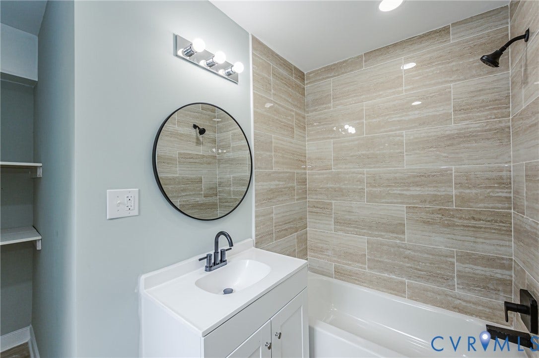 Modern vanity with integrated sink, circular mirror, and chrome light fixture