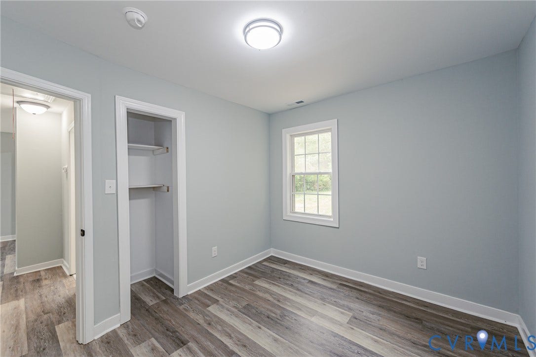 Wood-finish flooring throughout, light blue wall paint, white trim, and a window with white framing