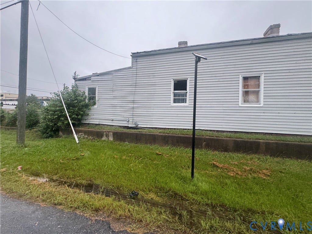 1400 N 29th Street, Richmond, VA 23223 Exterior elevation featuring light-colored horizontal siding, two windows, and a concrete foundation wall
