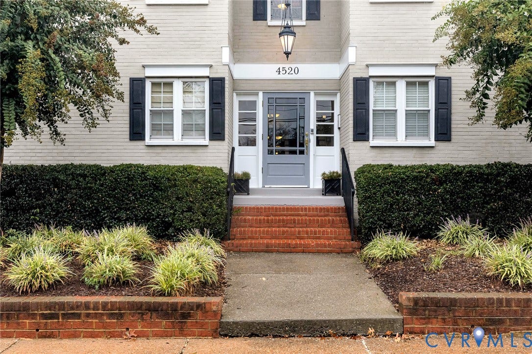 4520 Grove Avenue, #U5, Westhampton, Richmond, VA 23221 White brick exterior with black shutters, mature shrubs, brick steps, and a gray entry door