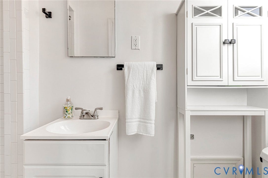 4520 Grove Avenue, #U5, Westhampton, Richmond, VA 23221 White vanity with an integrated sink, polished chrome faucet, built-in medicine cabinet, and vertical wall tiling