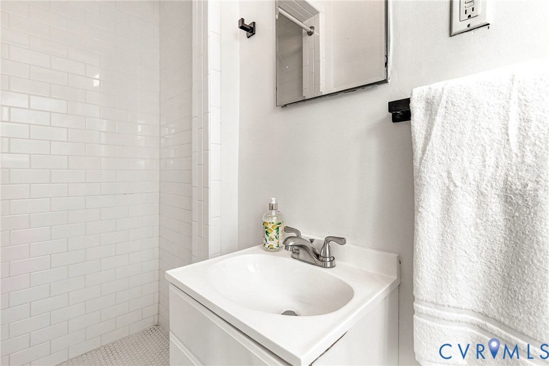 4520 Grove Avenue, #U5, Westhampton, Richmond, VA 23221 White subway tile shower enclosure with a mosaic tile floor, white vanity with integrated sink, and wall-mounted mirror
