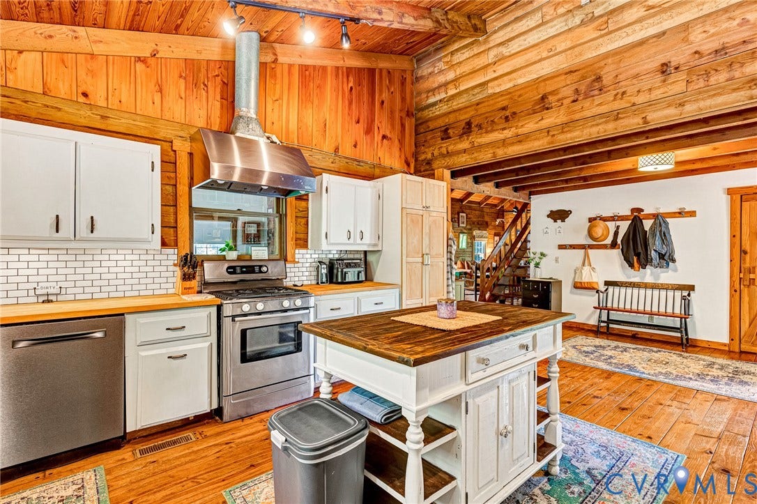 8328 Peaks Road, Hanover, VA 23069 Wood-paneled walls and ceiling, stainless steel appliances, white subway tile backsplash, butcher block countertops, and a kitchen island with storage