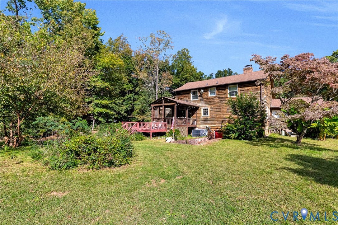 8328 Peaks Road, Hanover, VA 23069 Rustic exterior with log siding, a covered porch, an expansive wood deck, and a mature tree providing shade
