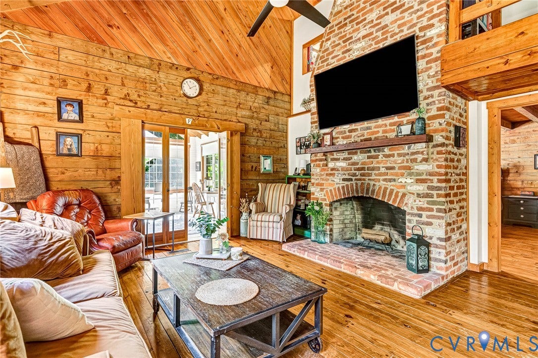 8328 Peaks Road, Hanover, VA 23069 Vaulted wood-paneled ceiling, wood-plank walls, brick fireplace with mantel, wood-finish flooring, and glass-paneled double doors
