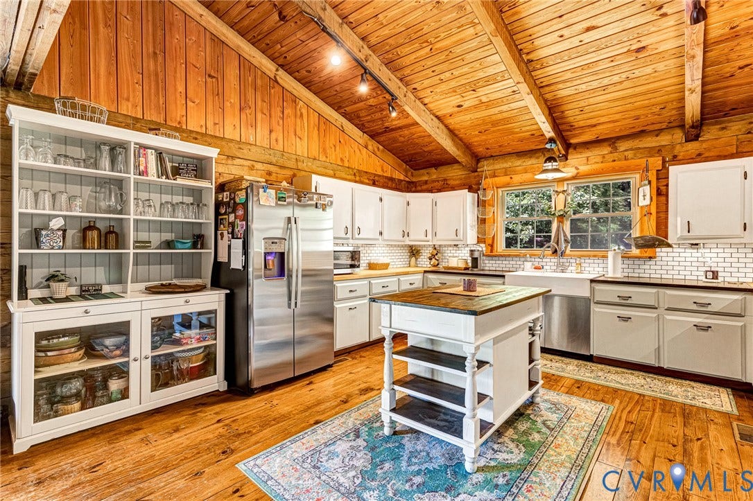 8328 Peaks Road, Hanover, VA 23069 Hardwood flooring, vaulted wood-paneled ceiling, white cabinetry, subway tile backsplash, and a stainless steel refrigerator