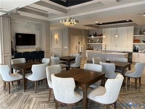 Herringbone-patterned wood-finish flooring, coffered ceiling, built-in cabinetry, wall paneling, and integrated kitchen island