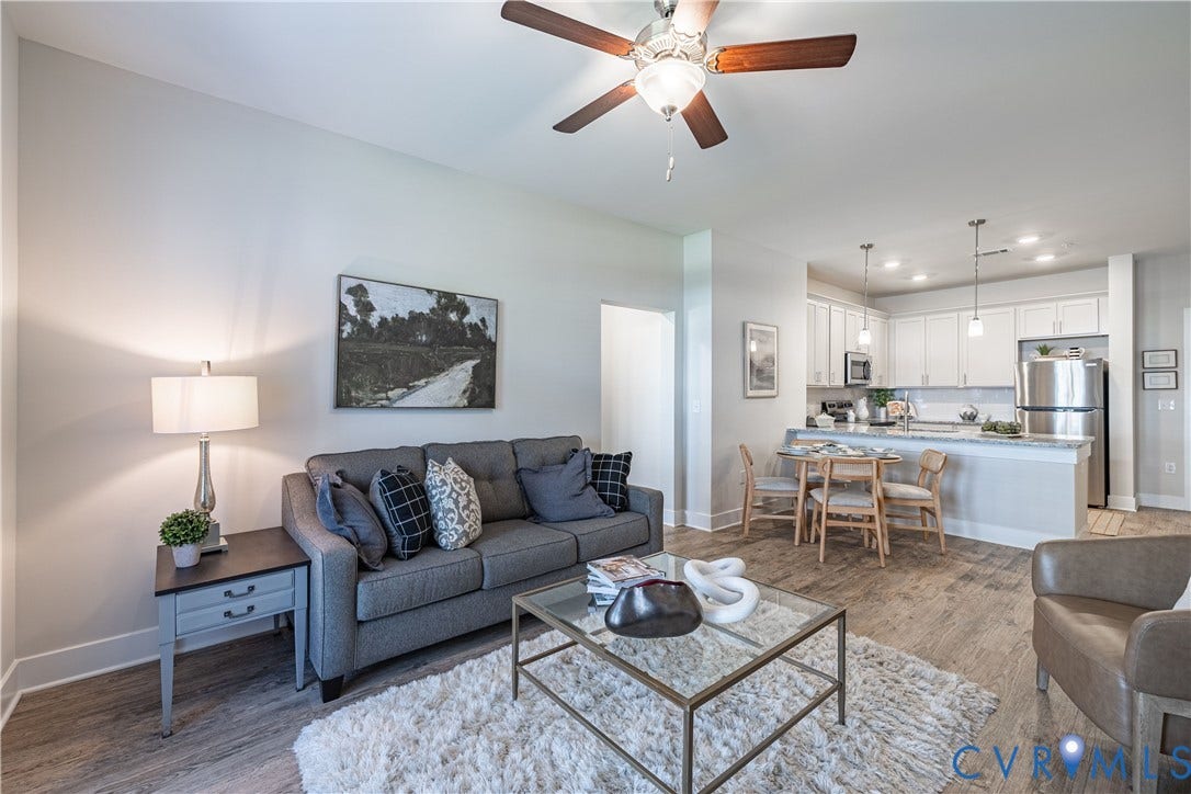 Open-concept living space featuring wood-finish flooring, a ceiling fan with integrated lighting, and recessed lighting