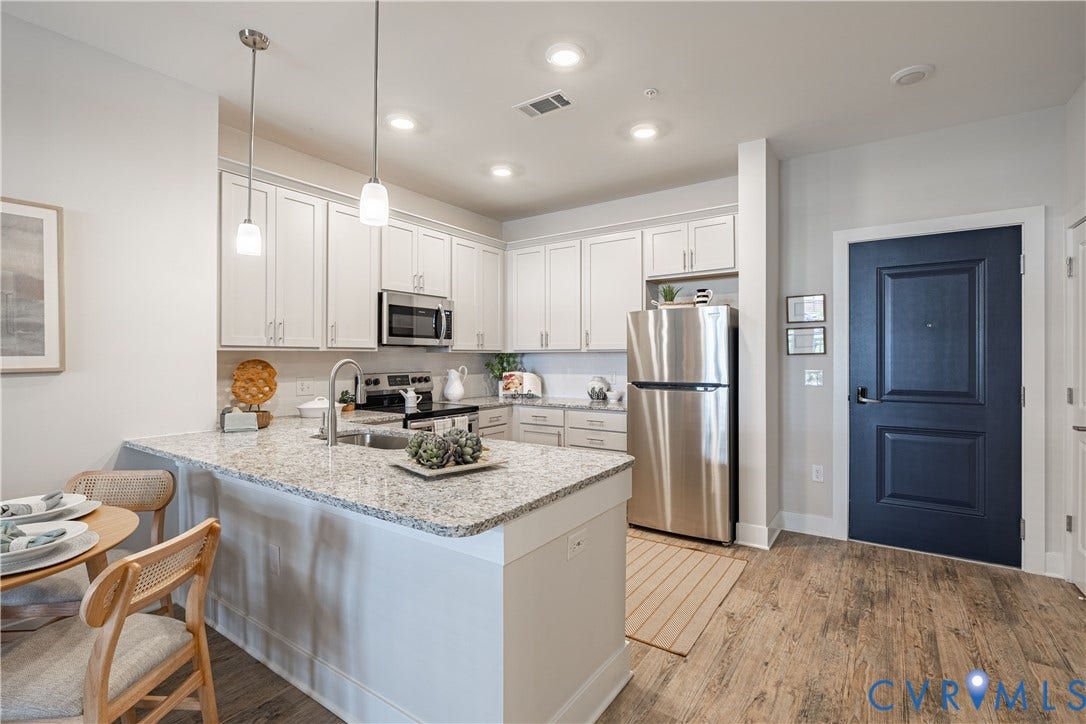 Kitchen featuring white shaker-style cabinetry, stainless steel appliances, granite countertops, wood-finish flooring, and pendant lighting