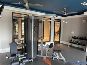 Fitness area featuring a multi-station exercise machine, kettlebell rack, rubber flooring, and two ceiling fans