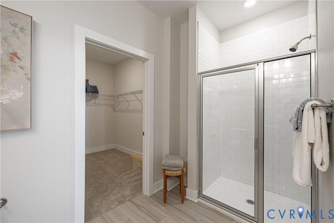 White subway tile shower with a frameless glass enclosure and a brushed nickel showerhead