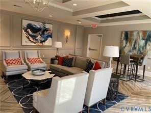 Tray ceiling with recessed lighting, decorative wall paneling, geometric chandelier, wood-finish flooring, and a built-in high-top counter