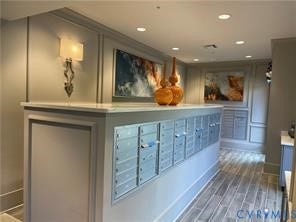 Custom mailbox bank featuring individual units, decorative wall sconces, recessed lighting, wood-finish flooring, and crown molding