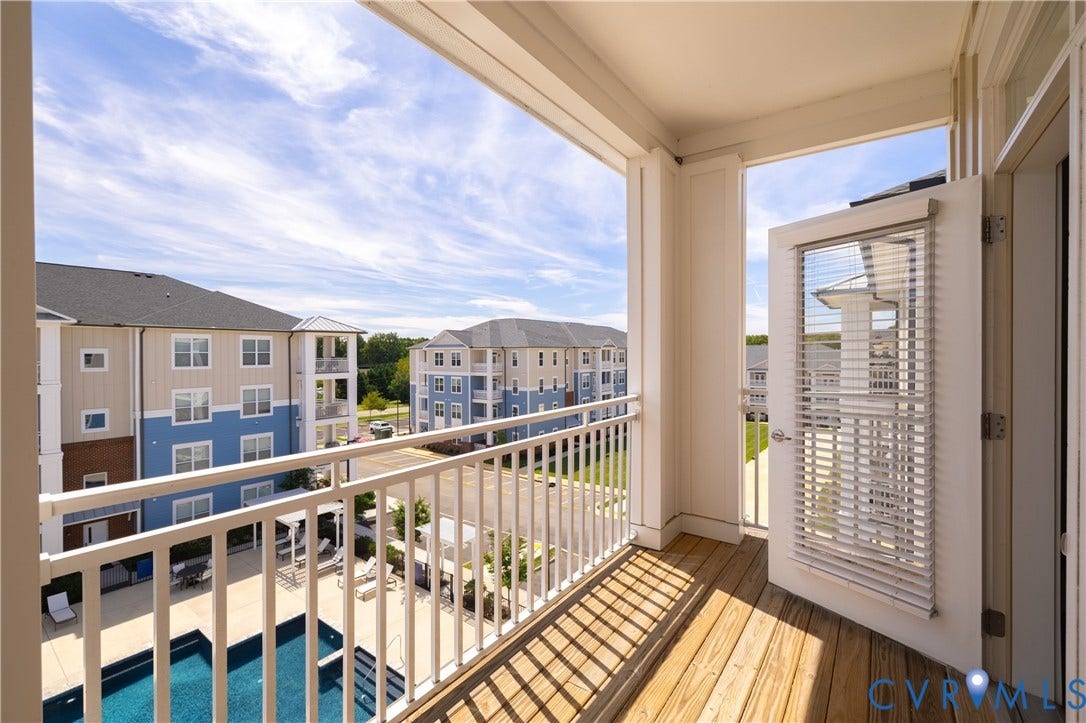 Private balcony with wood-finish flooring and a white railing
