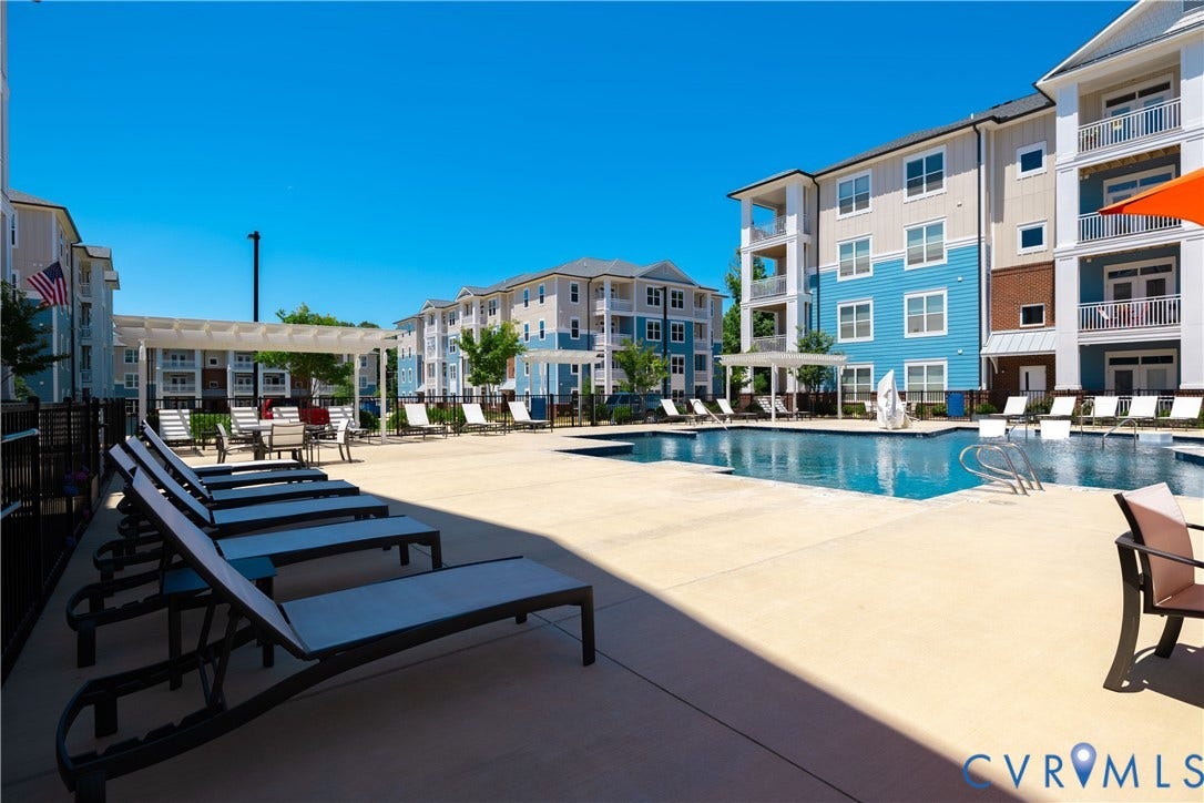 Resort-style swimming pool with integrated lounge seating, surrounding concrete sun deck, and multiple pergolas