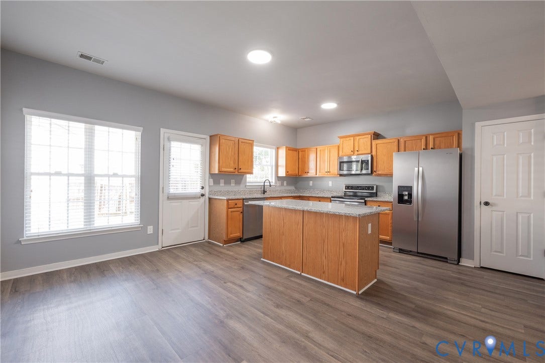 Family Room with access to the yard and steps to the kitchen with new flooring and paint