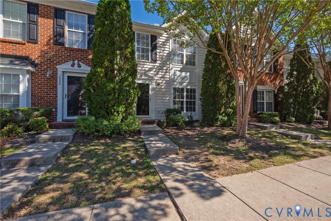 Brick and siding exterior with mature trees and established landscaping