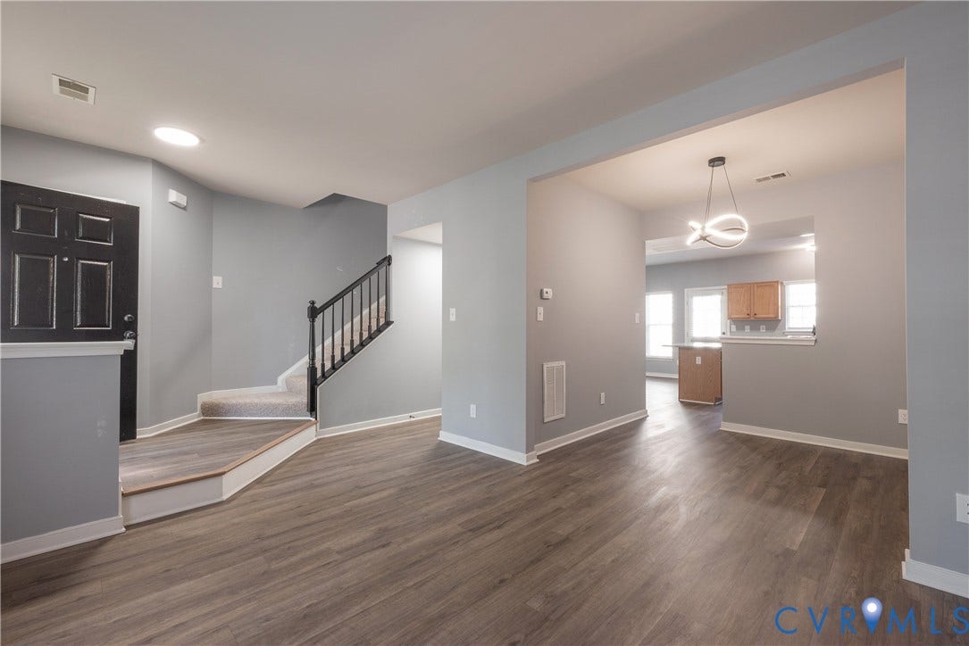New flooring throughout, carpeted staircase with black railings, opens to the dining room