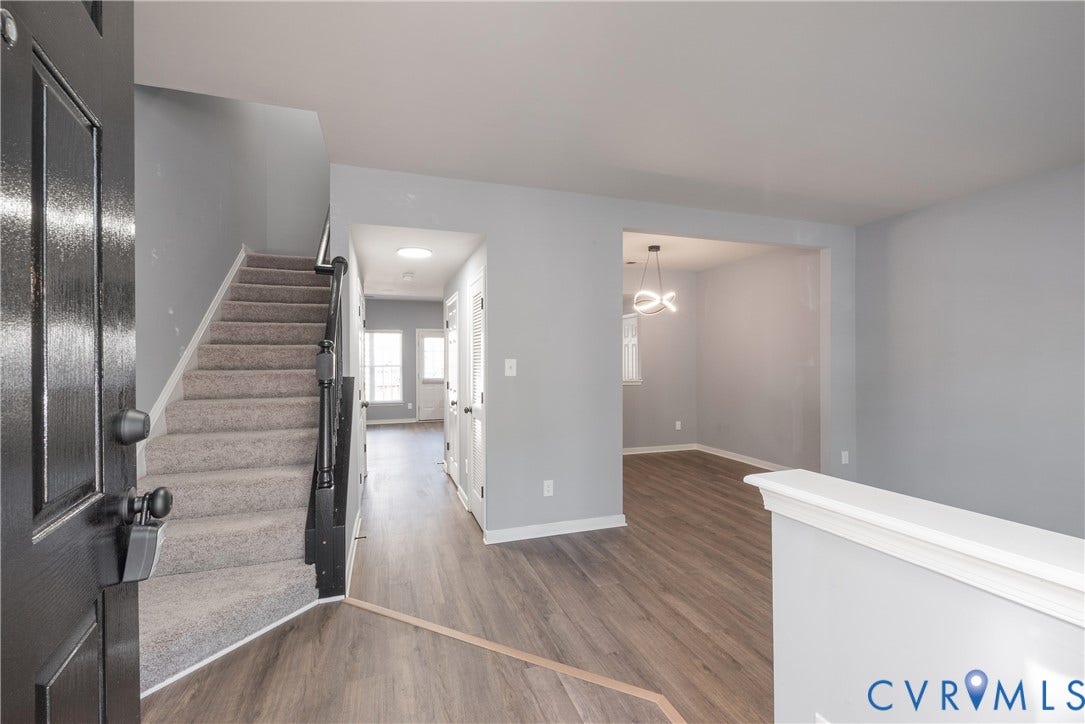 New flooring, carpeted staircase, neutral wall tones, decorative light fixture, and white trim