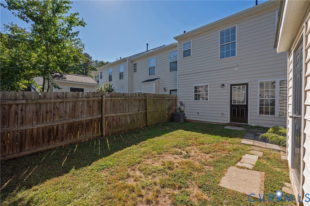 Private fenced yard with a wood fence, established lawn, and stepping stone pathway