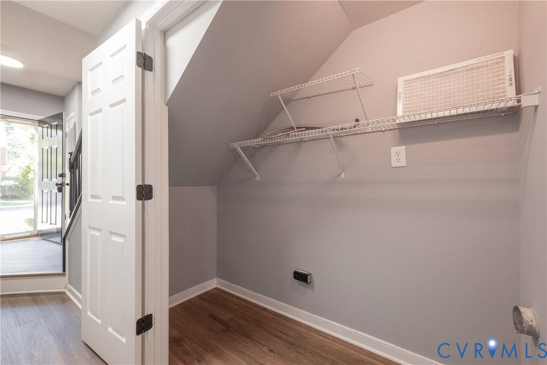 Sloped ceiling storage space with wire shelving, wood-finish flooring, and light gray walls