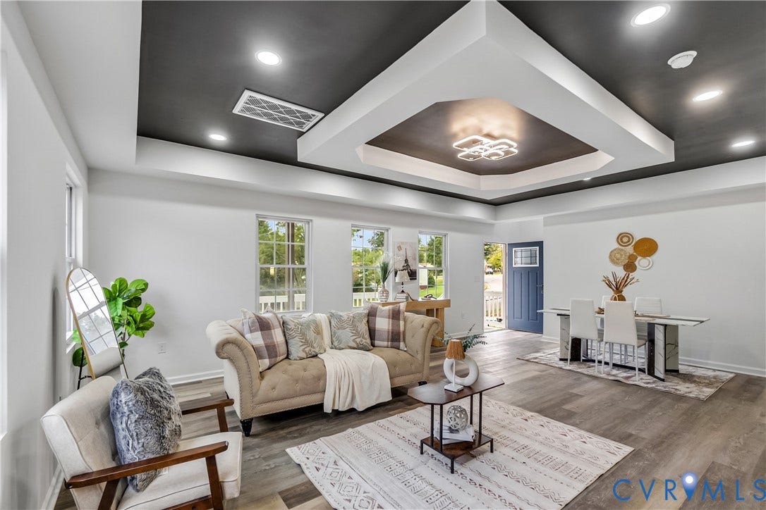 Open-concept living space featuring wood-finish flooring, recessed lighting, and a tray ceiling with a central fixture