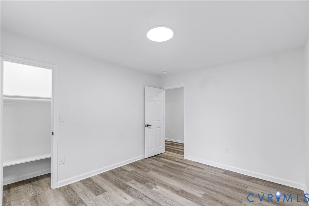 Wood-finish flooring, white walls, and a contemporary flush-mount ceiling light
