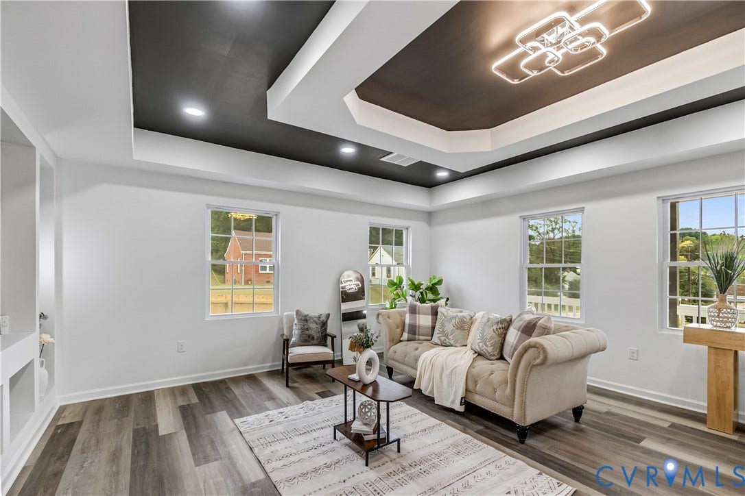 Tray ceiling with recessed lighting and a modern chandelier, wood-finish flooring, multiple windows, and built-in shelving