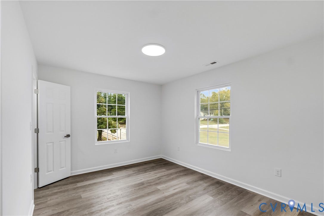 Bright interior with wood-finish flooring, white walls, and a contemporary flush-mount ceiling light