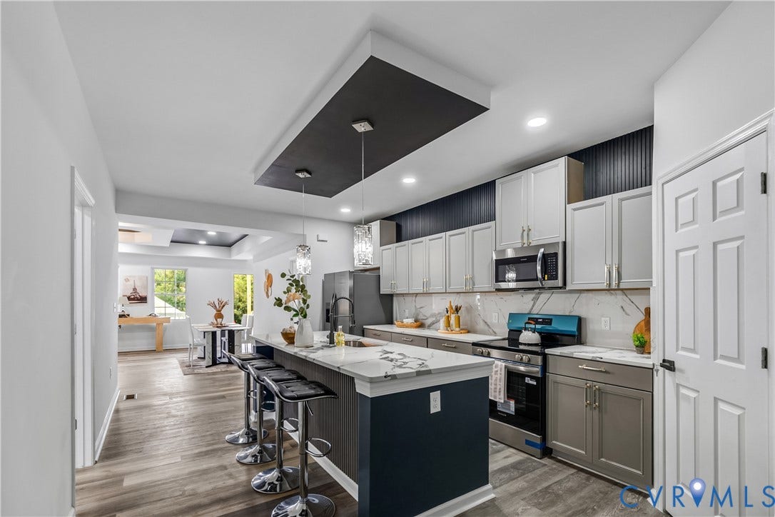 Kitchen with a multi-tone cabinet scheme, stainless steel appliances, and a central island with countertop seating