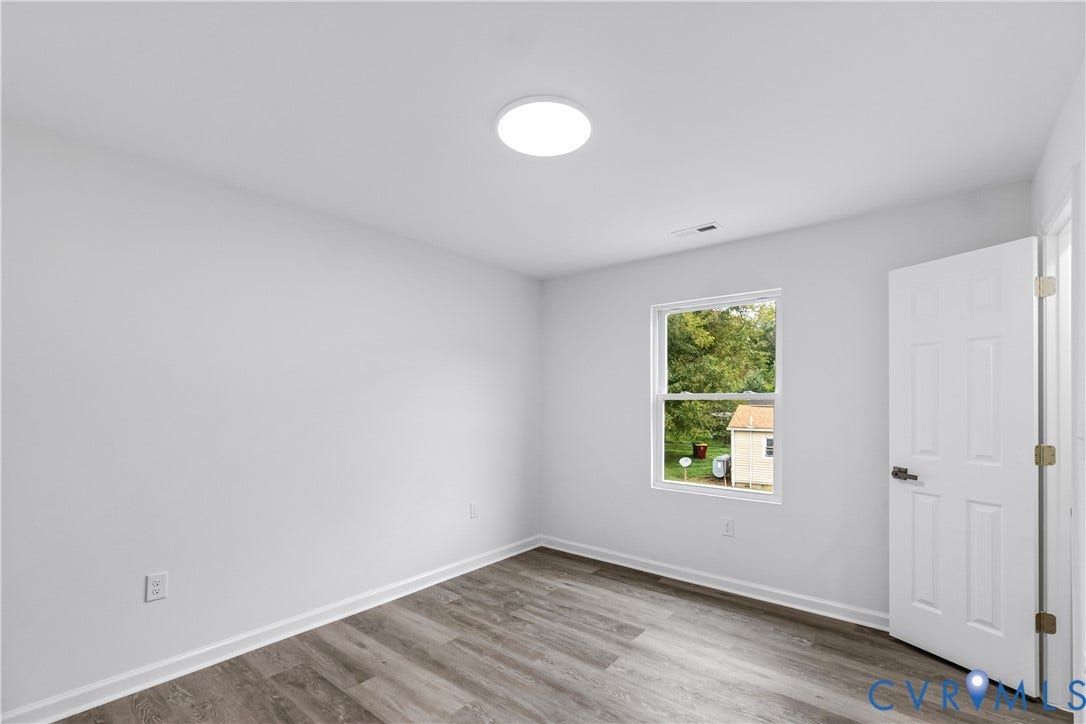 Wood-finish flooring with white baseboards and a ceiling-mounted light fixture