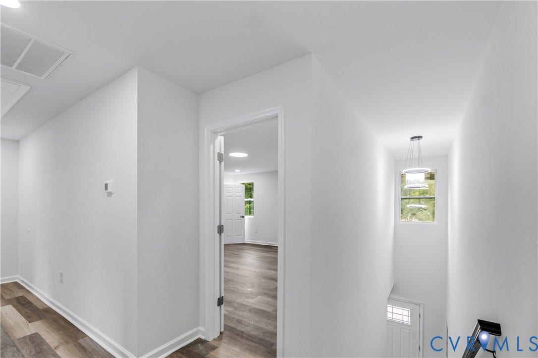 White walls and wood-finish flooring throughout the hallway