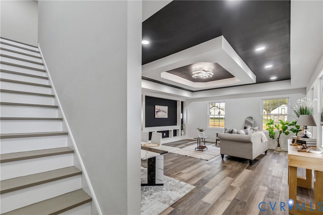 Spacious living area featuring wood-finish flooring and multiple windows